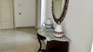 A hallway with a marble floor, a wooden bench, a decorative mirror, and a white door. - Crispi 2enty stylish flat at Spanish Steps (Roma)