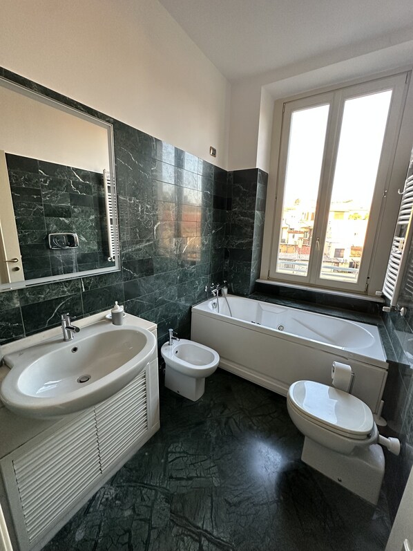 A bathroom with a sink, bidet, toilet, and bathtub. - Crispi 2enty: an elegant apartment near the Spanish Steps (Roma)