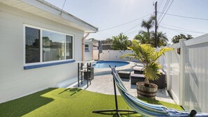 Un cortile con piscina, un'amaca e un piccolo patio.