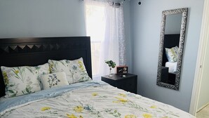 A bedroom with a floral bedspread, a dark headboard, and a bedside table with a radio. - Casita Chica (McAllen)