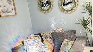 A living room with a sofa, two wall decorations with 'hello' and 'home' text, a framed picture, and a plant. - Casita Chica (McAllen)