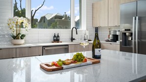 A modern kitchen with a large island, a wine bottle, and a glass of white wine. - Modern & Gorgeous Rooftop City Views & Close to the Best of Everything in SA! (San Antonio)