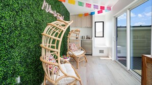 A balcony with wicker chairs, a green wall, and a kitchen area. - Modern & Gorgeous Rooftop City Views & Close to the Best of Everything in SA! (San Antonio)