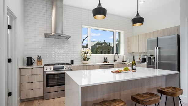 A modern kitchen with a large island, stainless steel appliances, wooden cabinets, and pendant lighting. - Modern & Gorgeous Rooftop City Views & Close to the Best of Everything in SA! (San Antonio)