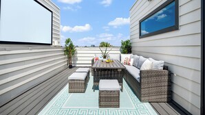 An outdoor patio with wicker furniture, a sofa, and a table. - Modern & Gorgeous Rooftop City Views & Close to the Best of Everything in SA! (San Antonio)