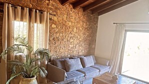 A cozy living room with a stone wall, a sofa set, a coffee table, and a potted plant. - Casa Prima (Monticello)