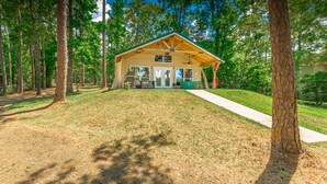 A wooden cabin with a porch, a barbecue grill, and a flagpole.