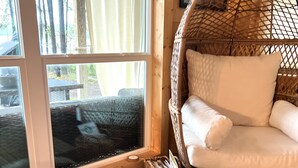 A cozy room with a large window, a wicker chair, a pet bed, and a woven basket.