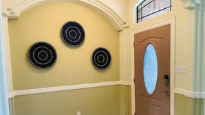 A hallway with three circular wall decorations, a door with a frosted glass panel, and a light switch on the wall. - Sundown Stay (San Juan)