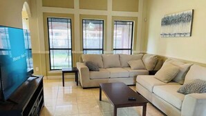 A living room with a sectional sofa, a coffee table, and a TV on a stand. - Sundown Stay (San Juan)