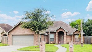 A two-story brick house with a front garage, a small front porch, and a well-maintained lawn. - Sundown Stay (San Juan)