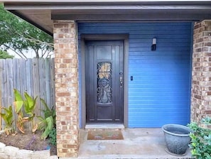Uma casa com porta azul escura, um pilar de tijolos e uma porta de garagem azul.