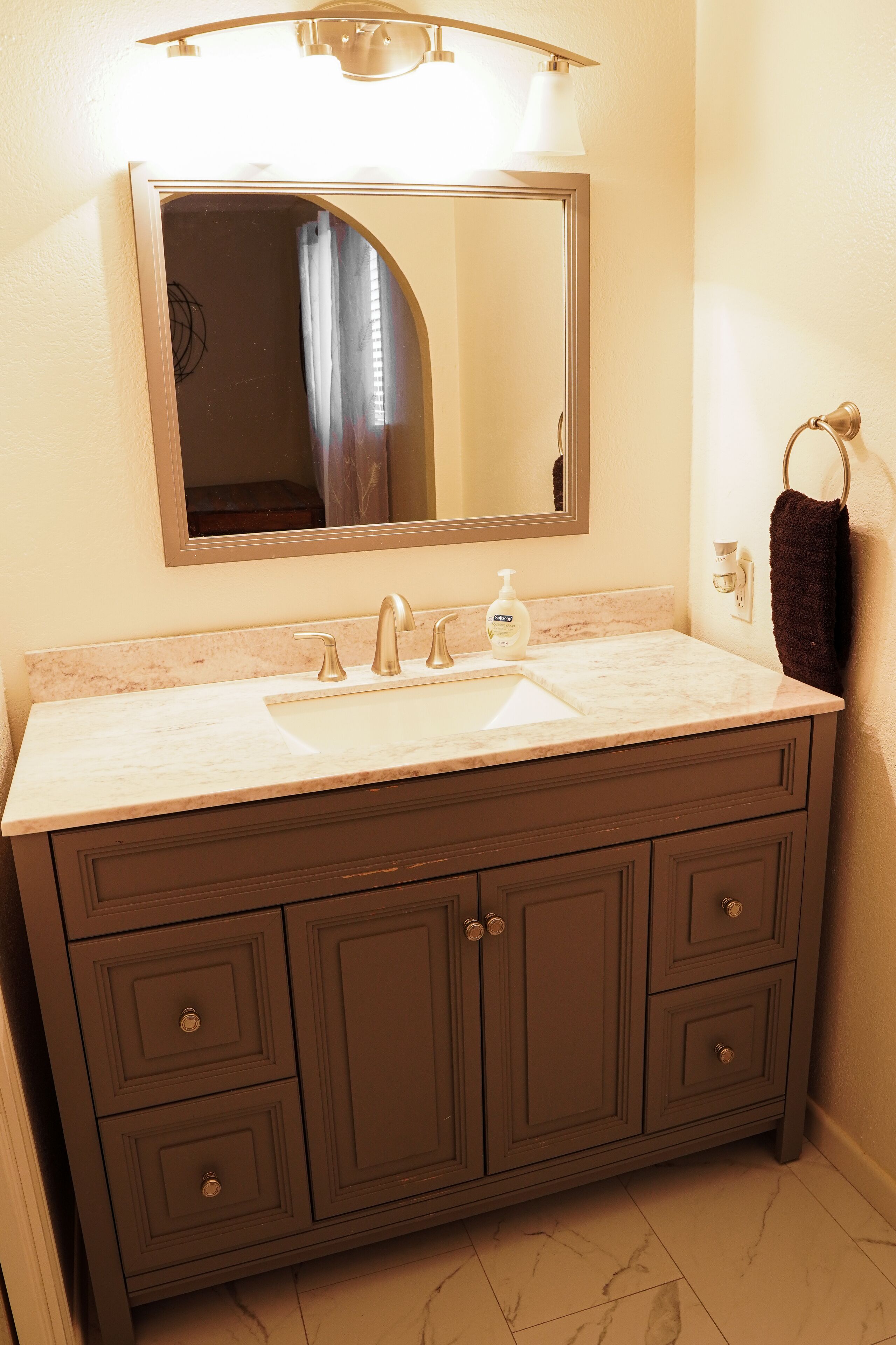 A bathroom with a marble sink, dark wooden vanity, and a mirror above the sink.