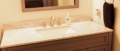 A bathroom with a marble sink, dark wooden vanity, and a mirror above the sink.