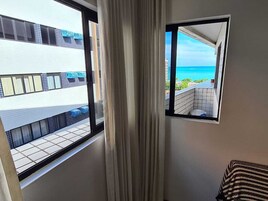 Quarto com vista para uma varanda e o oceano.