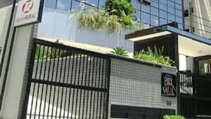 A modern building with a glass facade, a gated entrance, and a sign indicating a business or office space. - Apartamento Catamarã Portiville (Maceió)