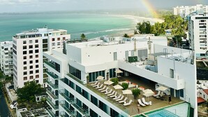 Un hotel con piscina en la azotea, vistas a la playa y un arcoíris.
