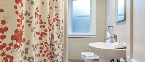 A bathroom with a toilet, sink, and window.