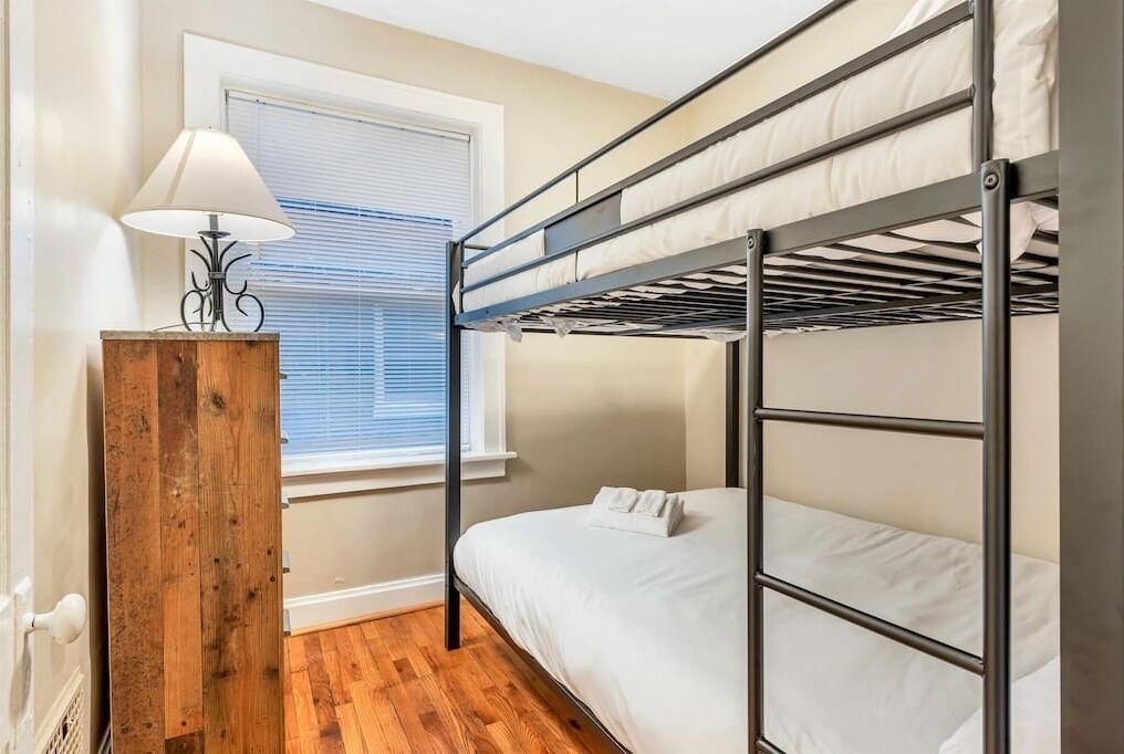A bunk bed room with a wooden nightstand and a lamp.