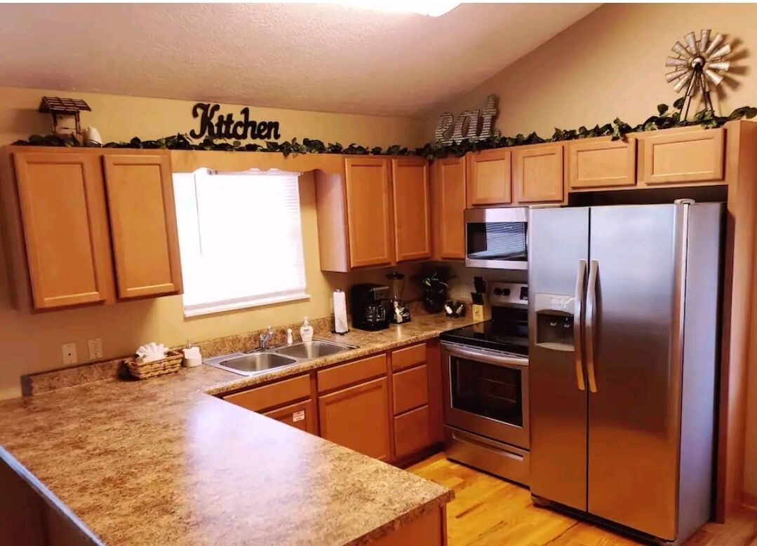 A kitchen with wooden cabinets, a stainless steel refrigerator, an oven, and a microwave.