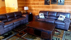 A log cabin interior with two leather sofas, a wooden coffee table, and a rug with animal prints. - 2 Bedroom  Cabin inside Pigeon Forge (Pigeon Forge)