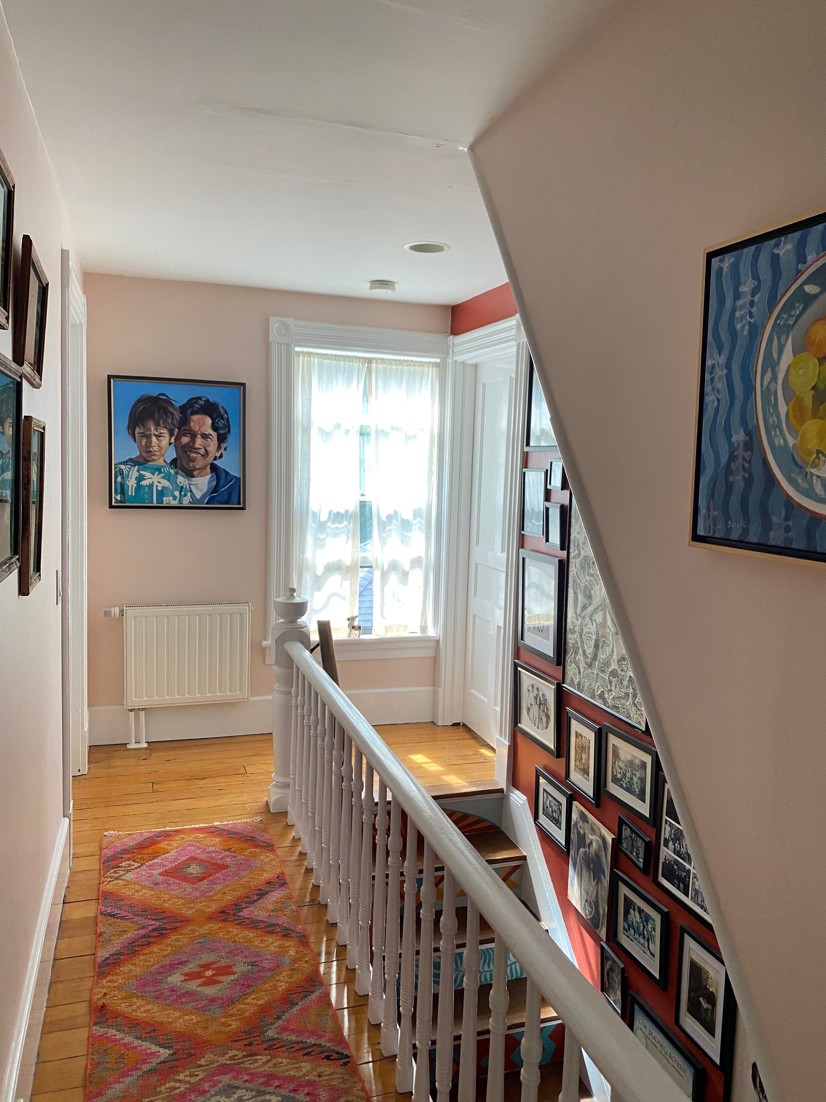 A staircase with a patterned carpet leading to a landing with a white railing.