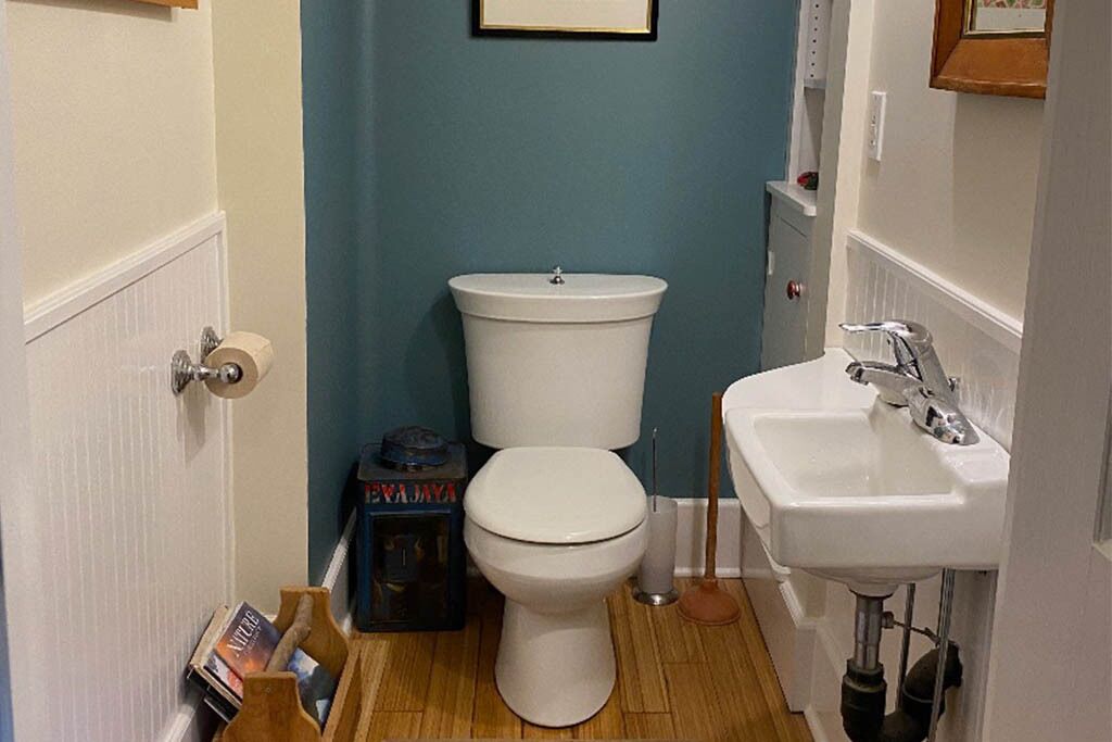 Un baño pequeño con inodoro blanco, lavamanos y pared azul.