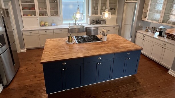 Una cocina con una isla central, armarios blancos y una sección inferior azul.