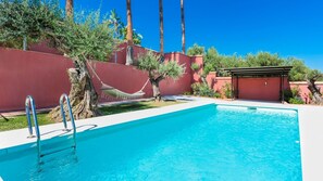 Una piscina con escaleras metálicas, una hamaca y una estructura pequeña al fondo.