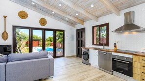 A modern kitchen with a built-in oven, dishwasher, and a large window overlooking a swimming pool.