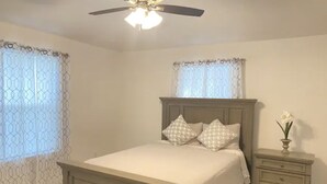 Ein Schlafzimmer mit Bett, Nachttisch und Deckenventilator.