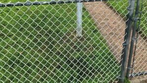 Una casa roja de dos pisos con una puerta delantera blanca, un buzón y una valla de malla metálica al frente.