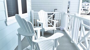 Une véranda avec deux fauteuils Adirondack et une petite table.