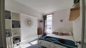 A bedroom with a bed, a wardrobe, a hanging basket, and a decorative wall piece. - Lovely 2 Bedroom Flat in the Heart of the City (Edinburgh)