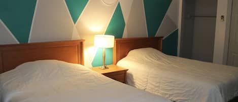 Ein Hotelzimmer mit zwei Betten, einem Nachttisch mit Lampe und einer Tür.