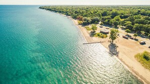 Vista aérea de una zona costera con playa, abundante vegetación y aguas turquesas cristalinas.