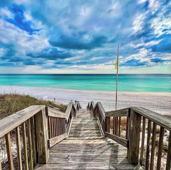 Walk along the boardwalk to the beach, where a flagpole stands in the distance.