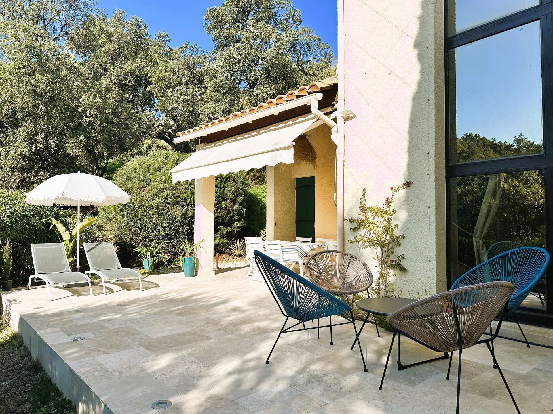 An outdoor patio with a table and chairs, a white umbrella, and a pergola structure.