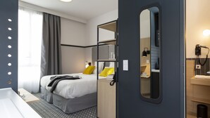 Een moderne hotelkamer met een bed, een bureau, een spiegel en een badkamer.