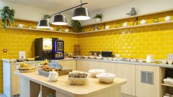 Une cuisine lumineuse avec des carreaux jaunes, un îlot central où sont disposés des aliments et un éclairage au plafond.