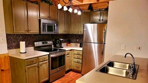 Una cocina con armarios de madera, electrodomésticos de acero inoxidable y piso de madera.