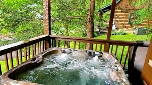 Un jacuzzi en una terraza de madera con vista a un paisaje verde.