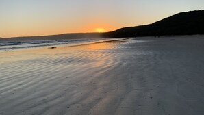 Ein Strand mit Sonnenuntergang im Hintergrund.