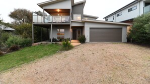 Ein modernes, zweistöckiges Haus mit überdachter Veranda, Garage und einem angelegten Vorgarten.