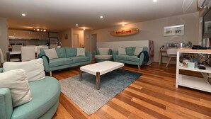 Ein modernes Wohnzimmer mit türkisfarbenen Sofas, einem weißen Couchtisch und Holzboden.