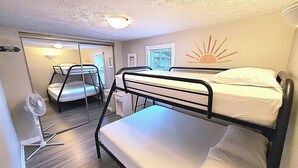 A bunk bed room with a ceiling fan, a window with blinds, and a wall decoration of a sun. - Summer Beach Family Cottage  🏖 2min→beach @ Bamboo Chalet ~ Lake Erie 🇨🇦 
 (Turkey Point)