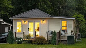 A small, single-story house with a porch, a carport, and a green lawn. - Summer Beach Family Cottage  🏖 2min→beach @ Bamboo Chalet ~ Lake Erie 🇨🇦 
 (Turkey Point)
