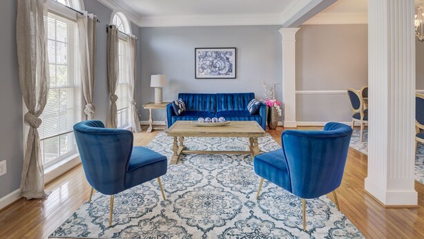 A living room with a blue sofa, two blue armchairs, a coffee table, and a patterned rug.