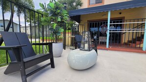 An outdoor seating area with a bench and a round table, surrounded by a metal fence and potted plants. - Sunny Palms Inn (Lake Worth)