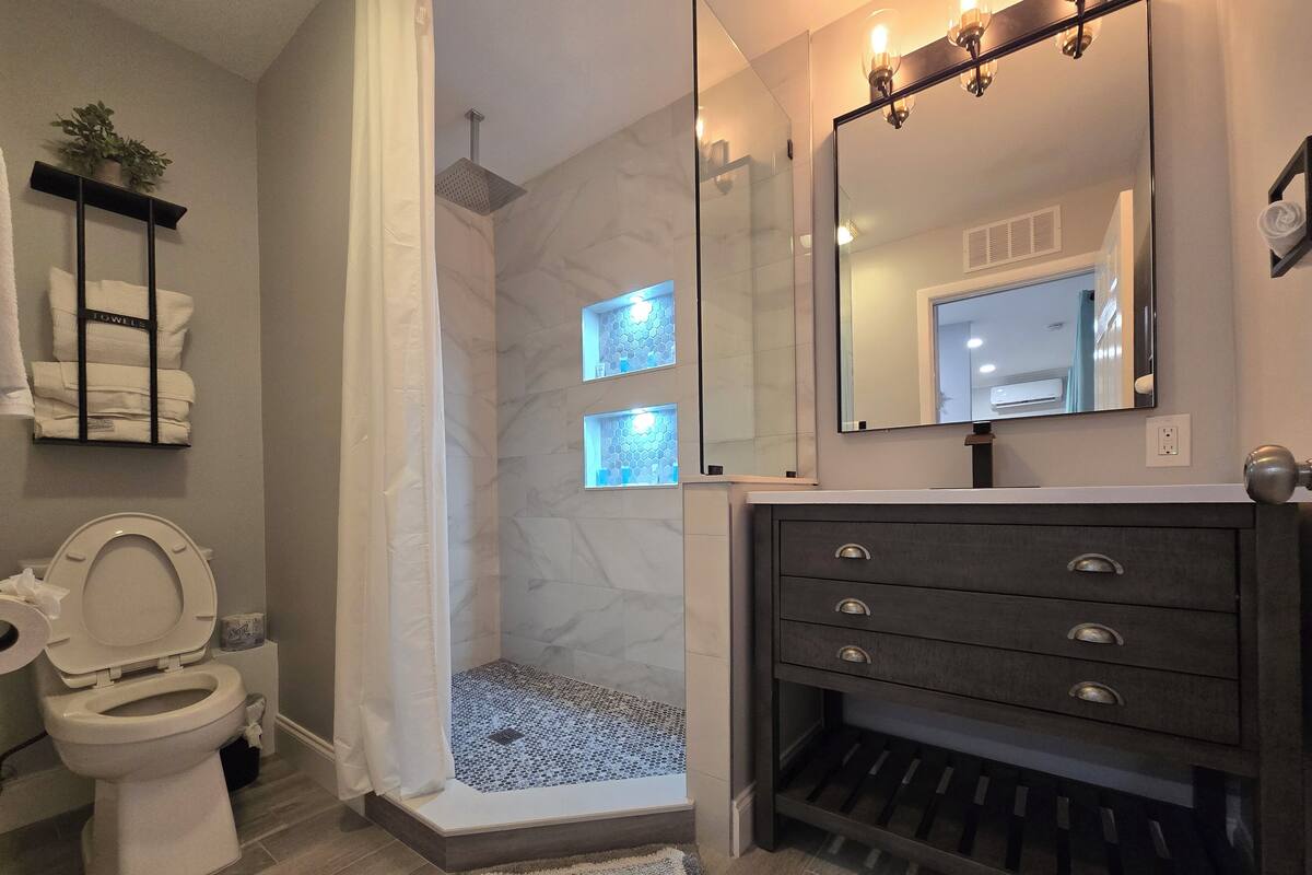 A modern bathroom with a shower, toilet, and vanity.